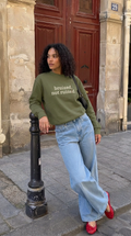 woman in a sweatshirt in front of a red door
